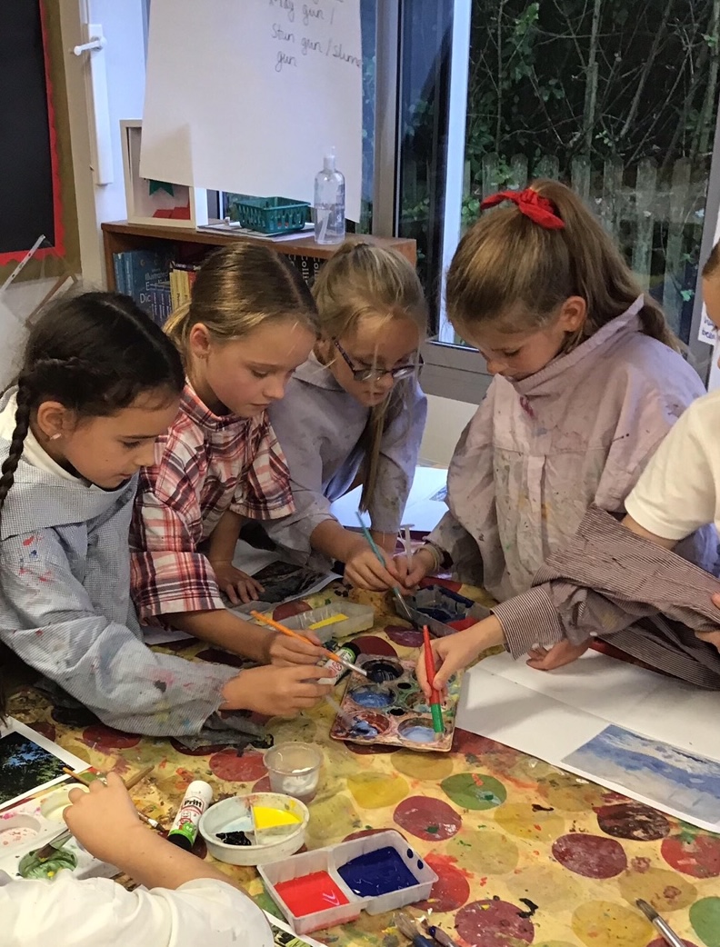 A group of girls sharing a paint palette in the classroom
